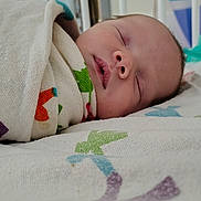 Jesse is registered to the contest to win money with this photo: newborn, baby, sleeping, hospital, crib, blanket, swaddled, infant, bed, face, peaceful, child, medical, healthcare, resting, indoors, colorful, soft, quiet, calm