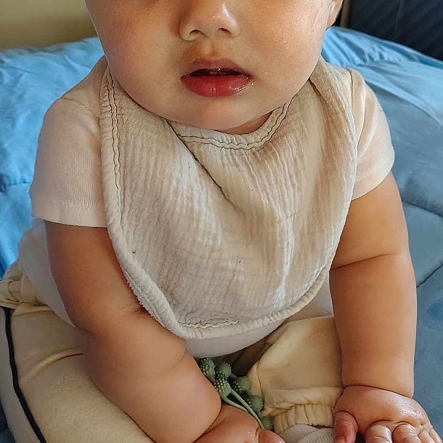 Jesse joined the competition — help win amazing prizes! baby, child, infant, sitting, portrait, indoors, bedroom, bed, blue_bedding, bib, cream_clothing, pants, socks, hands, face, wide_eyes, looking_at_camera, serious_expression, natural_light, home