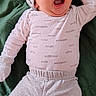 baby, blanket, casual, child, cozy, cute, gloves, green, hat, indoor, infant, lying_down, newborn, onesie, pants, person, sleepy, socks, soft_lighting, yawning
