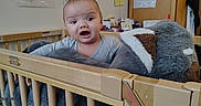 Jesse is registered to the contest to win money with this photo: baby, child, cozy, crib, curious, cute, expression, face, furniture, home, indoor, infant, person, portrait, room, soft_toy, stuffed_animal, wooden_crib, young_child