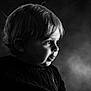 child, boy, portrait, black_and_white, side_profile, soft_lighting, curly_hair, sweater, close_up, face, expression, innocence, cute, studio, monochrome, young, person, head_and_shoulders, background, artistic