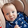 Jessica is registered to the contest to win money with this photo: baby, infant, child, face, blue_eyes, floral_clothing, fist, closeup, cute, soft_texture, seat, pink_cushion, portrait, young_child, indoors, expression, skin, person, apparel, newborn