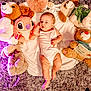 baby, infant, plush_toys, teddy_bear, stuffed_animal, blanket, white_clothing, floor_rug, purple_rug, soft_texture, lying_down, cute, child, indoor, toy, cozy, relaxed, comfort, infant_clothing, playtime