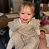toddler, child, smiling, blue_eyes, dress, tights, sitting, indoor, person, happy, face, hair, legs, hands, lap, blurred_background, cozy, cute, portrait, young_child
