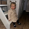 Kiara a rejoint le concours — aidez-le/la à gagner de superbes lots ! toddler, child, indoor, pigtails, beige_coat, black_shoes, rosy_cheeks, curious, standing, wooden_floor, blurred_background, door, shelf, person, portrait, cute, fashion, young_child, casual, home