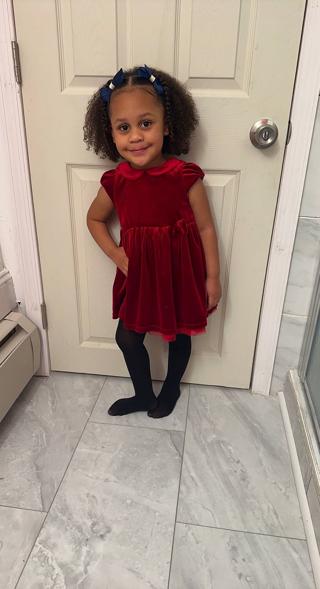 Leilani is registered to the contest to win money with this photo: baby_toddler_clothing, door, dress, floor, flooring, hair, human_leg, joy, knee, leg, long_hair, magenta, person, purple, sleeve, smile, standing, thigh, toddler, trunk