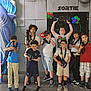 Jean participe au concours pour gagner de l'argent avec cette photo : arcade, casual_clothing, children, colorful, diverse, elephant_statue, exit_sign, floor, fun, glasses, group, indoor, laser_tag_guns, playful, posing, red_chair, shark_statue, signage, smiling, toilet_sign