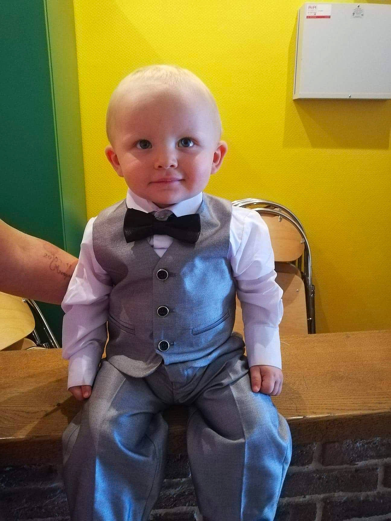 Morgan a rejoint le concours — aidez-le/la à gagner de superbes lots ! baby, cheek, child, formal_wear, head, outerwear, person, sitting, smile, standing, suit, tie, toddler, toy, tuxedo, yellow