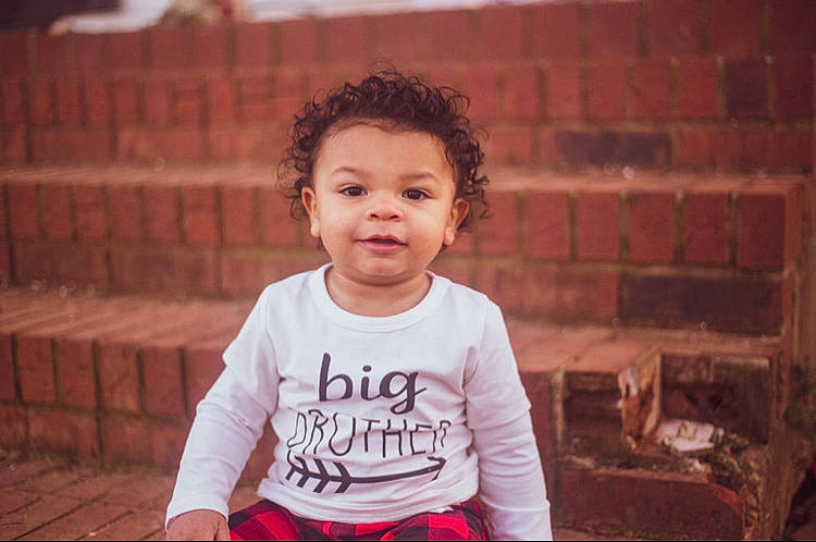 Liam joined the competition — help win amazing prizes! baby_toddler_clothing, brick, brickwork, child, facial_expression, flash_photography, fun, happy, joy, laugh, person, portrait, portrait_photography, room, sitting, sleeve, smile, t_shirt, toddler, wood