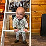 baby, blanket, child, cozy, cute, fabric, feet, floor, hands, home_interior, indoor, ladder, onesie, person, playful, smiling, standing, warm_lighting, wood_floor, wooden_wall