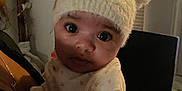 Aubrey is registered to the contest to win money with this photo: baby, child, hat, fuzzy_hat, bear_ears, indoor, person, adult, holding, close_up, curious, cozy, window_blinds, soft_lighting, clothing, face, portrait, infant, cute, warm