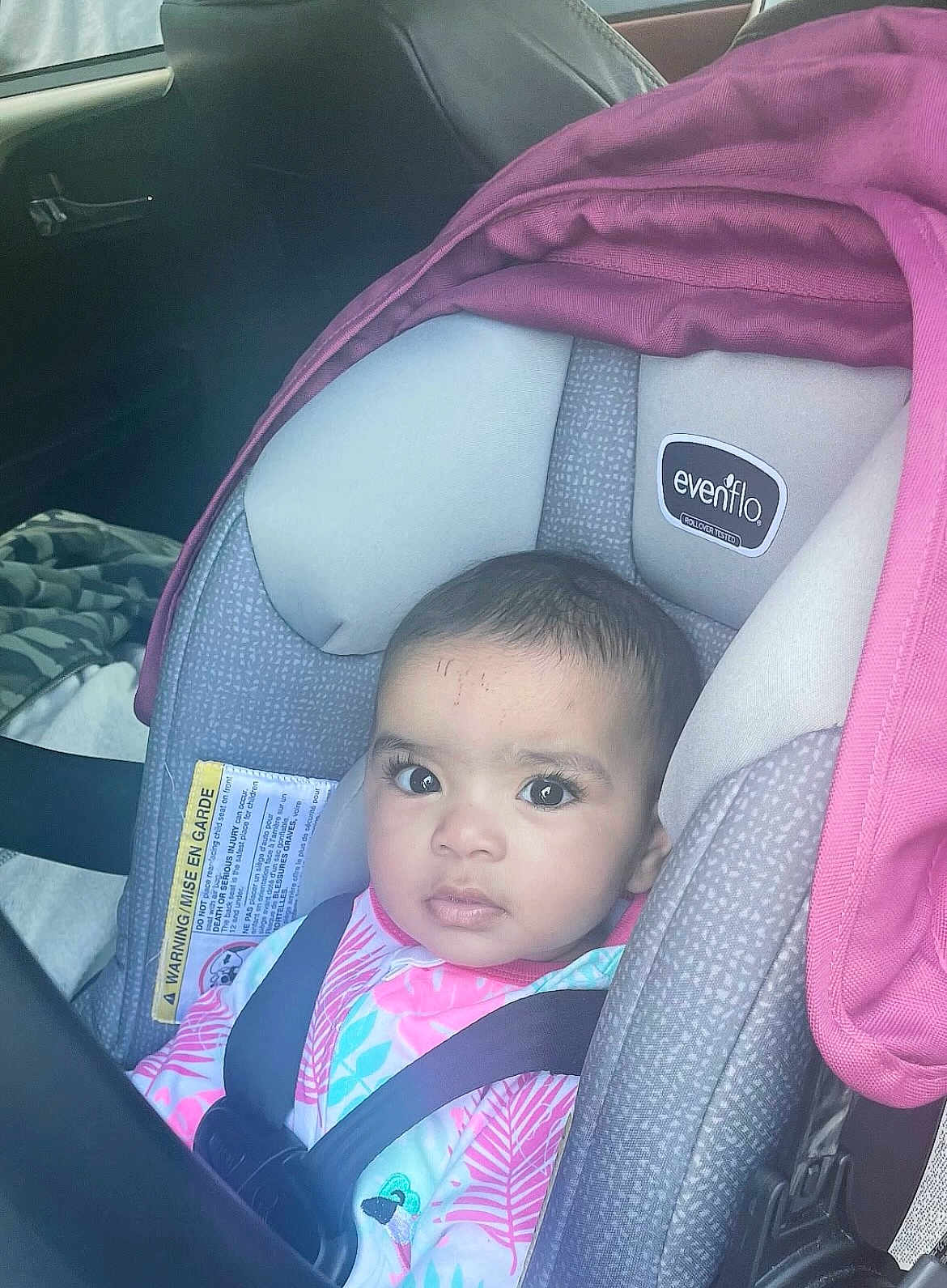 Aubrey is registered to the contest to win money with this photo: baby, car_seat, child, seat_belt, infant, car_interior, pink, gray, clothing, person, face, sitting, young_child, portrait, seat, straps, looking, indoors, eyes, head