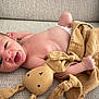baby, newborn, infant, smiling, plush_toy, bunny, couch, fabric, texture, child, happy, cute, skin, hand, lying_down, indoors, soft_toy, comfort, relaxed, small