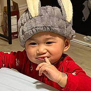Celine Duyen Lam is registered to the contest to win money with this photo: baby, child, portrait, smiling, bunny_hat, red_outfit, indoor, bedroom, cozy, closeup, face, hand, finger, cute, infant, sitting, soft_hat, fuzzy, playful, photography