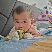 Celine is registered to the contest to win money with this photo: baby, bed, bedroom, blanket, chewing, child, comfort, curious, cute, face, head, indoor, infant, lying_down, mittens, pillow, sleepwear, small_person, soft_toys, toy