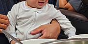 Celine joined the competition — help win amazing prizes! adult, baby, bowl, bracelet, casual, child, clothing, family, food, hand, indoor, metal_bowl, person, phone, relaxed, seated, smiling, spoon, table, vegetables