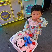 Celine is registered to the contest to win money with this photo: arcade, arcade_machine, child, claw_machine, colorful, dress, entertainment, family_friendly, floor, girl, indoors, patterned_clothing, photography, plush_toys, portrait, shopping, standing, thoughtful, toddler, toy_basket
