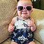 Alayia is registered to the contest to win money with this photo: baby, cheeks, child, clothing, couch, cute, dress, floral_pattern, furniture, hair, hand, happy, indoor, infant, legs, person, pink, sitting, smile, sunglasses