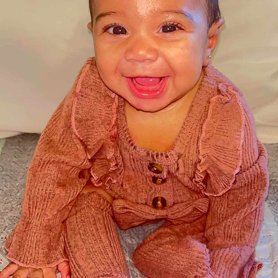 Orion is registered to the contest to win money with this photo: baby, babylaughing, clothing, crawling, face, happy, head, knitwear, person, photography, portrait, sitting, smile, sweater