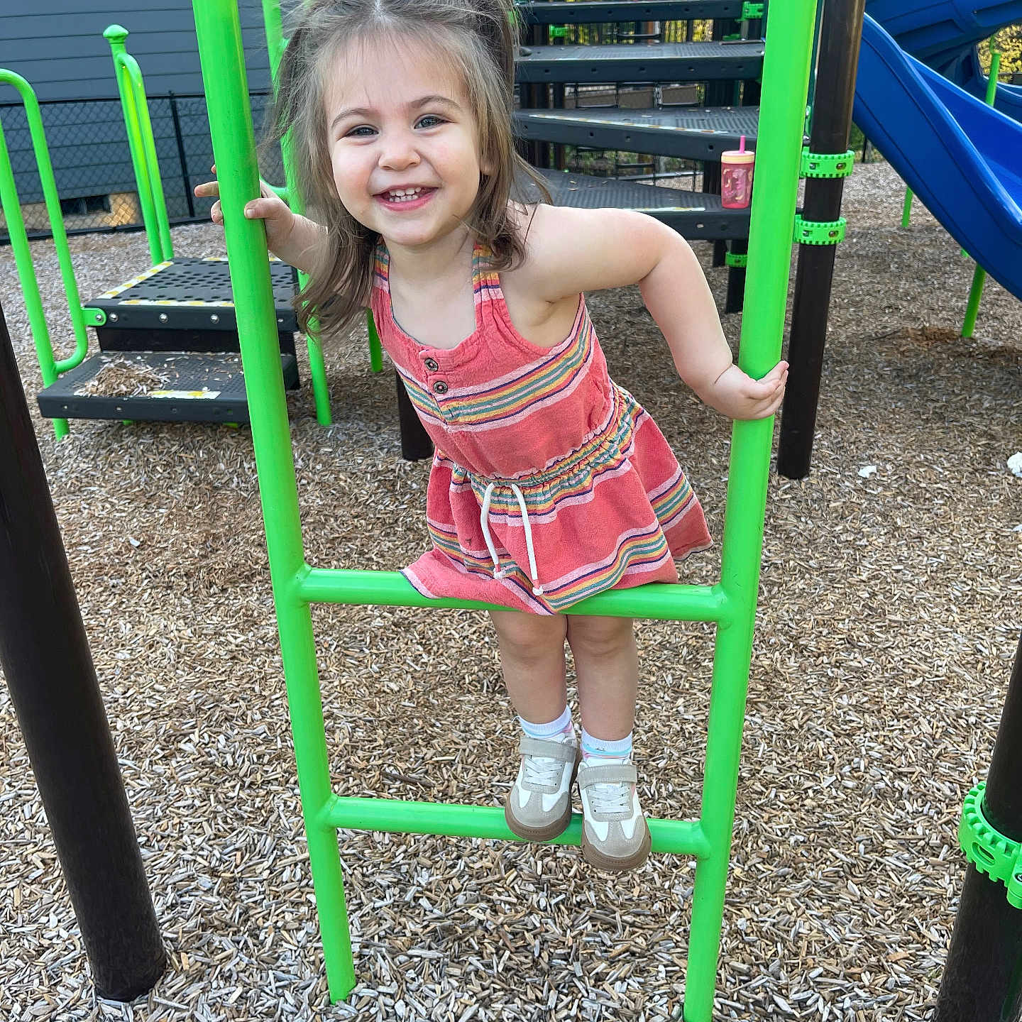 Scarlett is registered to the contest to win money with this photo: casual_clothing, child, climbing, daylight, dress, fun, girl, green_bars, happy, joy, outdoor, park, play_equipment, playground, recreation, shoes, smiling, socks, wood_chips, young_child