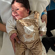 Line a rejoint le concours — aidez-le/la à gagner de superbes lots ! baby, newborn, infant, onesie, teddy_bear, blanket, adult_hand, smile, dark_hair, hospital_wristband, nail_art, cozy, soft_fabric, portrait, closeup, bed, clothing, skin, happy, sitting