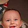 Paxtyn is registered to the contest to win money with this photo: baby, brown, child, closeup, clothing, cushion, eyes, face, happy, hat, head, indoors, infant, joyful, mouth, person, portrait, smiling, teeth, texture