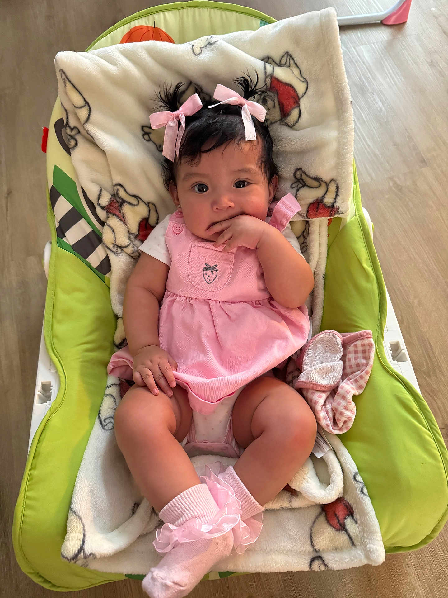 Ariana joined the competition — help win amazing prizes! baby, child, pink_dress, pink_bows, baby_seat, blanket, indoor, floor, socks, cute, infant, portrait, person, baby_girl, hand_in_mouth, curious, seated, cozy, plush_blanket, wooden_floor