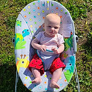 Cali joined the competition — help win amazing prizes! baby, child, infant, baby_seat, outdoor, grass, sunlight, colorful, animal_print, red_pants, barefoot, summer, nature, cute, relaxed, playful, seat, person, green, daylight