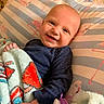 Cali joined the competition — help win amazing prizes! baby, smiling, blanket, pillow, flamingo_pattern, infant, child, cute, happy, blue_clothing, face, portrait, indoors, relaxing, young_child, cozy, pacifier, soft_texture, lying_down, comfort