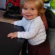 Milann participe au concours pour gagner de l'argent avec cette photo : adult, arm, blond_hair, child, clothing, cute, face, floor, furniture, hand, happy, home, indoor, long_sleeve, pants, person, smiling, table, toddler, toy_car