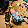 baby, denim_overalls, tool, wheel, cardboard, stroller, wrench, pliers, drill, socket, floor, happy, person, infant, hand, foot, workshop, carpet, smile, repair