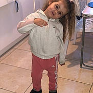 Mia participe au concours pour gagner de l'argent avec cette photo : child, girl, indoor, tile_floor, jacket, pink_pants, adidas, long_hair, hair_tied, standing, pose, kitchen, cabinet, chair, footwear, curious, playful, head_tilt, person, floor