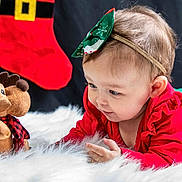 Zay'Ah is registered to the contest to win money with this photo: baby, child, plush_toy, moose, red_clothing, green_clothing, headband, christmas_stocking, holiday_theme, fluffy_rug, toy, portrait, curious, indoor, cute, smiling, festive, holiday_decor, person, closeup