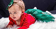 Zay'Ah is registered to the contest to win money with this photo: baby, child, infant, red_clothing, green_skirt, headband, bow, fluffy_surface, white_texture, smiling, portrait, cute, holiday_theme, indoor, studio, young_child, lying_down, happy, face, person