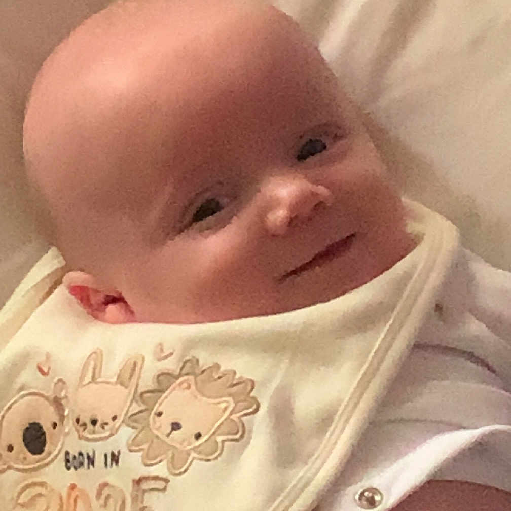 Karter joined the competition — help win amazing prizes! adorable, animal_print, baby, bib, child, closeup, clothing, comfort, cute, face, happy, head, infant, lying_down, newborn, peaceful, portrait, skin, smile, soft_surface