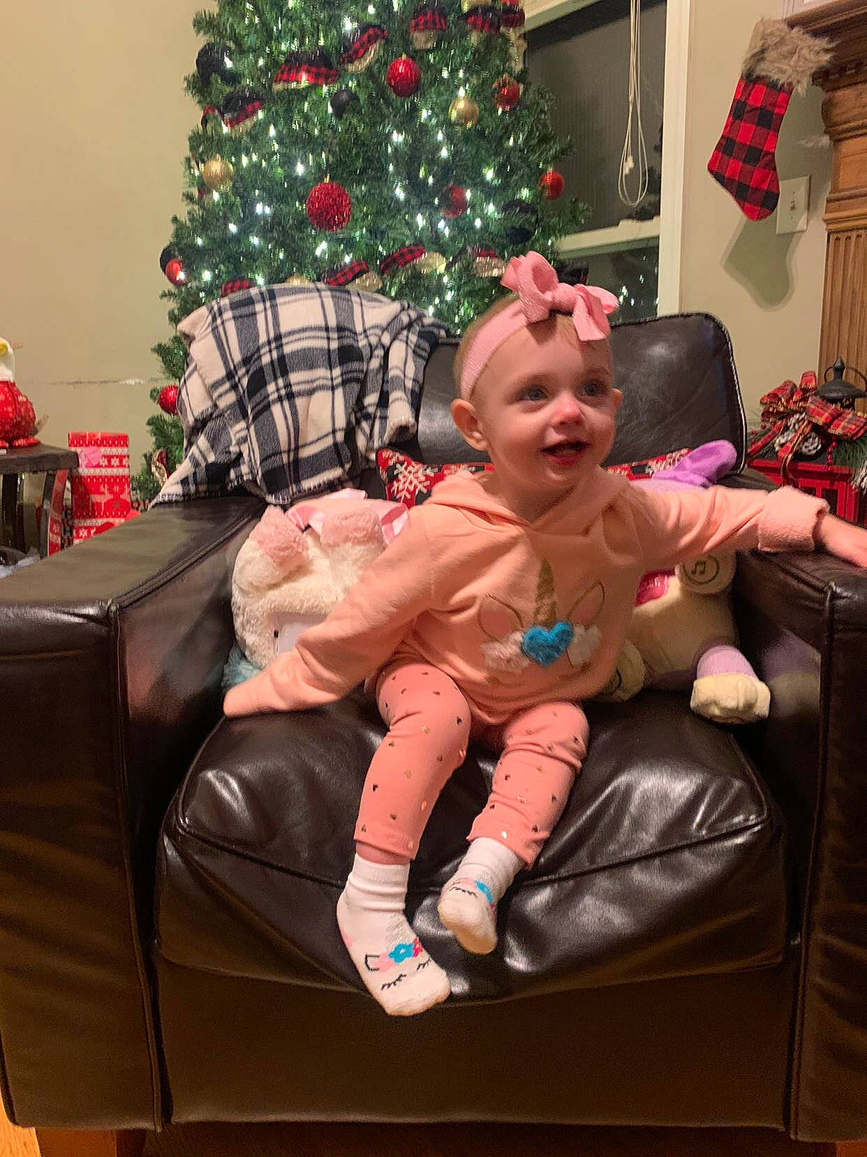 Maddison is registered to the contest to win money with this photo: baby, child, christmas, christmas_decoration, christmas_eve, christmas_ornament, christmas_tree, comfort, event, evergreen, fun, headwear, holiday, holiday_ornament, lap, living_room, ornament, person, pink, sitting