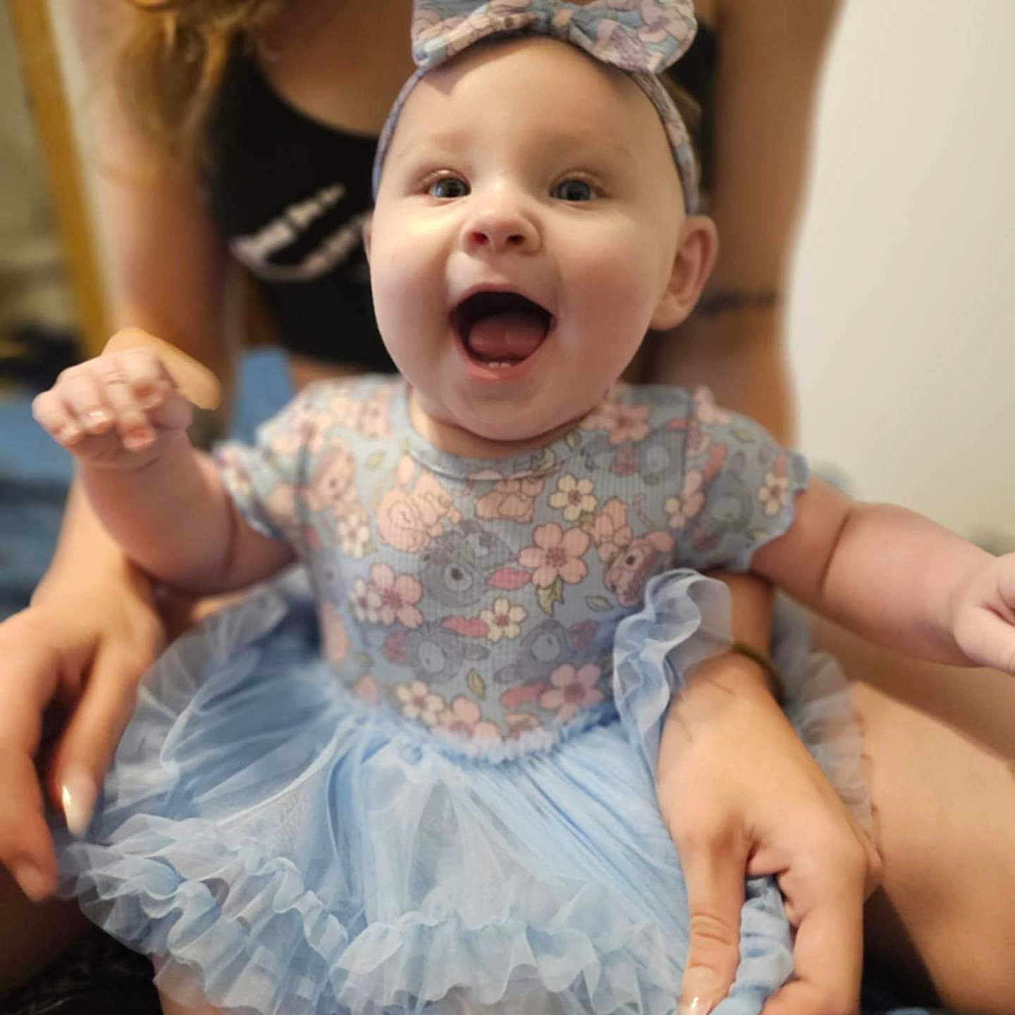 Quinnzel is registered to the contest to win money with this photo: apparel, baby, blue, celebration, child, cute, dress, fabric, floral, hands, happy, headband, indoors, joy, person, portrait, sitting, smile, tutu, young_child