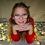child, girl, glasses, smile, long_hair, string_lights, lights, face, hands, red_clothing, indoor, portrait, happy, festive, blonde, young, cheerful, closeup, casual, cozy
