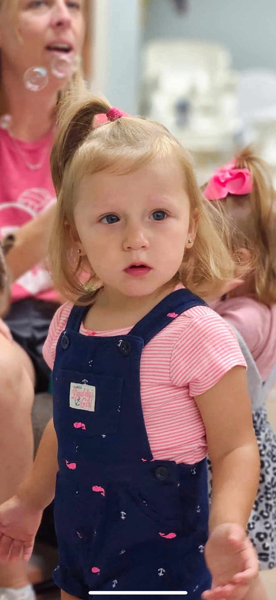 Maddie joined the competition — help win amazing prizes! toddler, child, girl, overalls, pink_stripes, hair_tie, indoor, woman, family, portrait, blurry_background, curious, casual_clothing, people, childhood, cute, pink_bow, person, young_child, blonde_hair