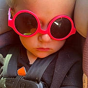 Maddie joined the competition — help win amazing prizes! toddler, child, sunglasses, pink, car_seat, harness, clothing, black, face, serious, hair, blond, closeup, seatbelt, infant, person, young_child, portrait, accessory, sun_protection