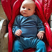 Charles participe au concours pour gagner de l'argent avec cette photo : baby, infant, blue_clothing, red_baby_seat, seat, cushion, indoor, child, person, cute, comfort, relaxing, portrait, small_hand, small_feet, face, looking, expression, cozy, casual