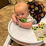 Brently is registered to the contest to win money with this photo: baby, high_chair, toy, floor, indoor, child, infant, chewing, colorful, clothing, furniture, play, person, seat, home, cute, young, expression, hand, face