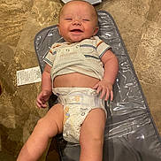 Brently is registered to the contest to win money with this photo: baby, infant, smiling, diaper, striped_shirt, changing_pad, floor, winnie_the_pooh, happy, cute, child, skin, person, lying_down, indoors, floor_tiles, baby_changing_station, playful, young_child, casual