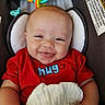 baby, smiling, red_shirt, blanket, toy, face, child, infant, happy, cushion, seat, closeup, cute, person, indoor, hand, head, expression, comfort, playtime