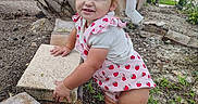 Hartley joined the competition — help win amazing prizes! toddler, child, barefoot, grass, dirt, concrete_block, palm_tree, outdoor, strawberry_pattern, clothing, cute, hair, mohawk, expression, nature, fence, garden, person, young_child, playful