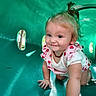 baby, child, crawling, playground, green_tunnel, smiling, cute, outdoor, sunlight, toddler, clothing, pink, hair, necklace, happy, person, skin, hand, face, play