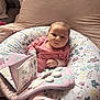Ayla-May is registered to the contest to win money with this photo: baby, infant, pink_clothing, floral_pattern, pillow, soft_toy, fabric_book, couch, indoor, child, cute, portrait, seated, home, cozy, relaxed, person, young_child, comfort, sleepwear