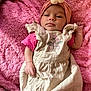 baby, infant, pink_blanket, headband, flower, dress, strawberry_embroidery, lying_down, clothing, soft_texture, cute, child, portrait, indoor, young_child, hands, face, expression, skin, cozy