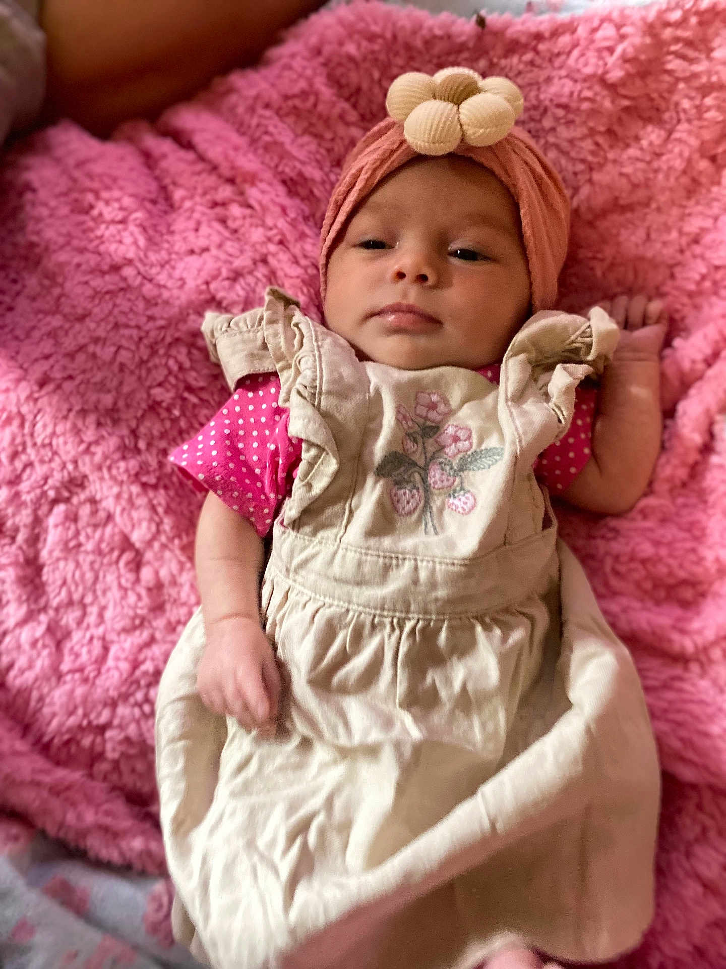 Joycelynn joined the competition — help win amazing prizes! baby, infant, pink_blanket, headband, flower, dress, strawberry_embroidery, lying_down, clothing, soft_texture, cute, child, portrait, indoor, young_child, hands, face, expression, skin, cozy