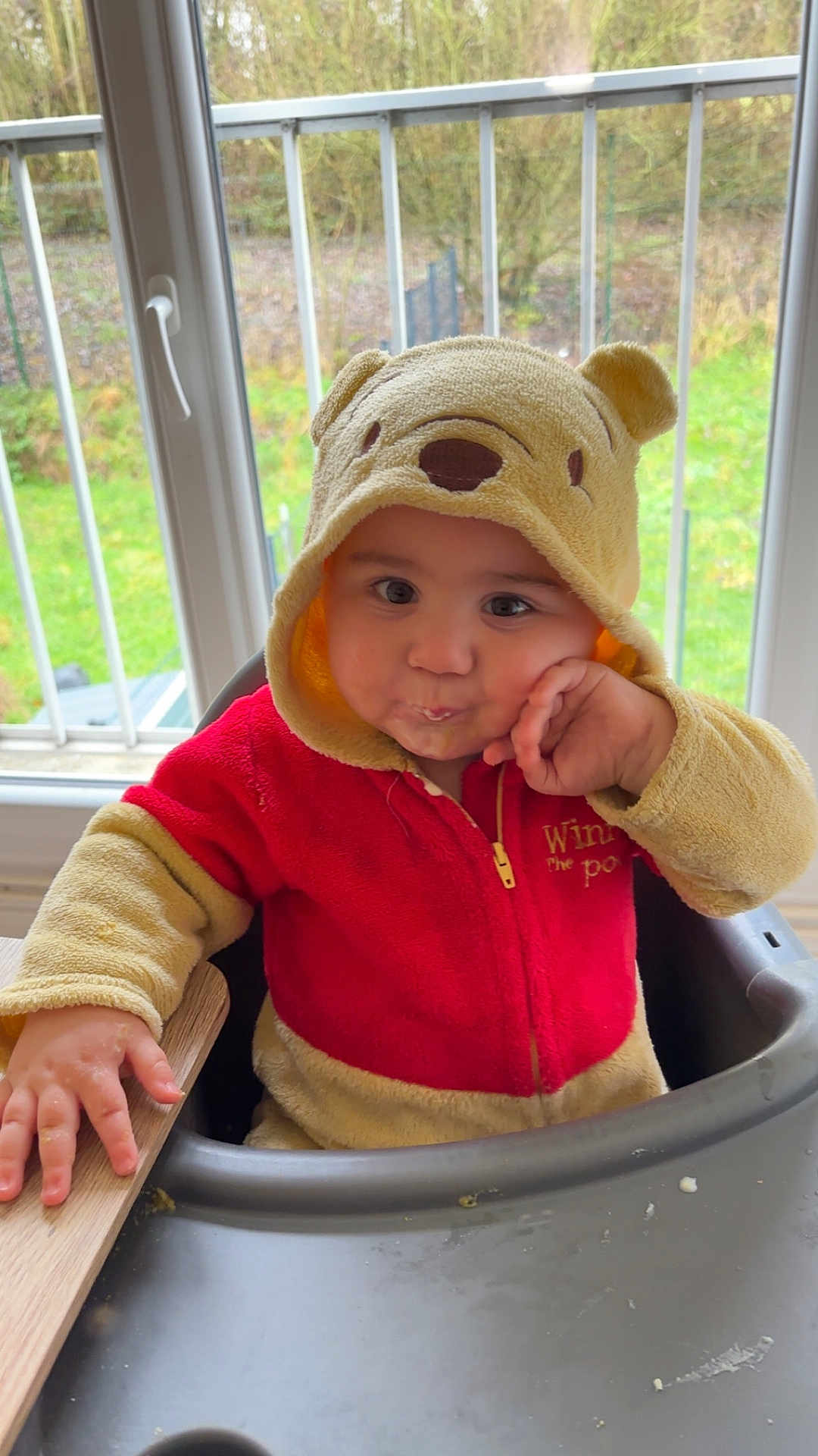 Maellan a rejoint le concours — aidez-le/la à gagner de superbes lots ! child, toddler, hoodie, winnie_the_pooh, red_clothing, yellow_clothing, high_chair, indoor, window, greenery, hand, face, cute, baby, person, seated, expression, contemplative, furniture, portrait